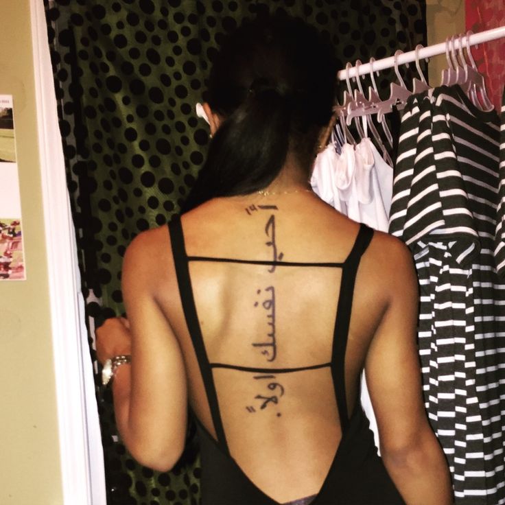 chica de espaldas con un tatuaje de frase arabe en la columna vertebral
