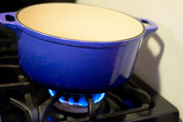 A large, blue, pot over a flame on the the stove.