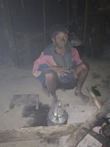 Chopa seated inside his hut besides the fireplace.