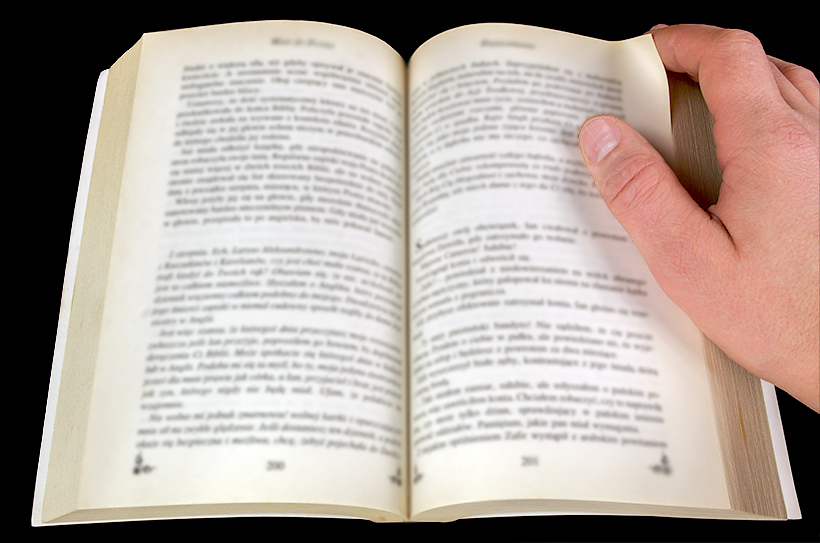 Mól książkowy - otwarta książka i dłoń trzymająca róg strony
