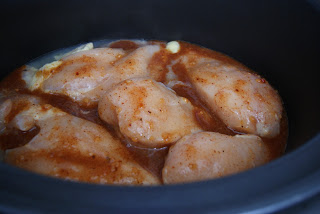 Seasoned chicken placed in a crockpot ready to be slow cooked.