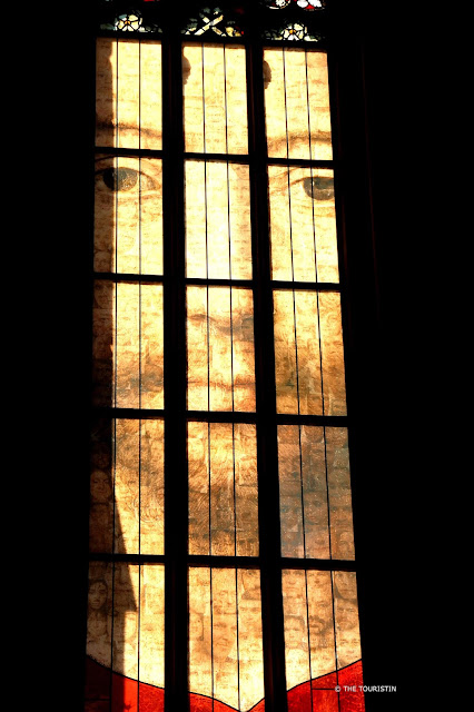 Church window with hundreds of small faces combined that result in one large one.