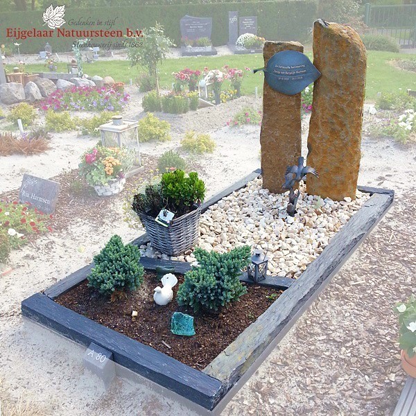 Grafmonument met basalt zuilen en bronzen blad