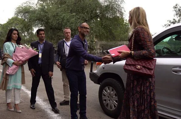 Queen Maxima wore a new asymmetrical paisley print long sleeve midi dress by Altuzarra. Chanel red bag, and red boots