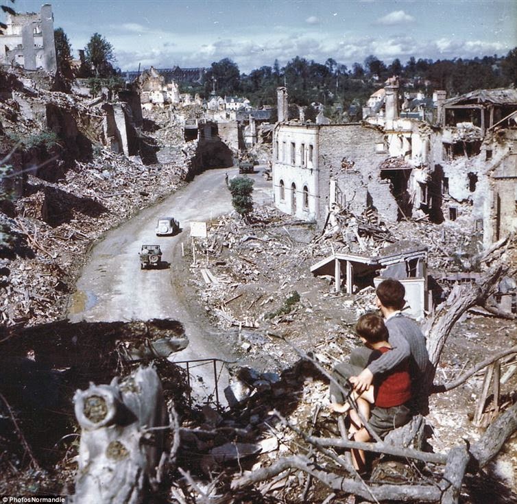 24 Rare Historical Photos That Will Leave You Speechless - The aftermath of D-Day as two boys watch from a tree while American soldiers drive through Saint Lo in France.