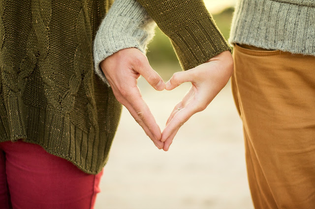 A couples hands making a heart shape