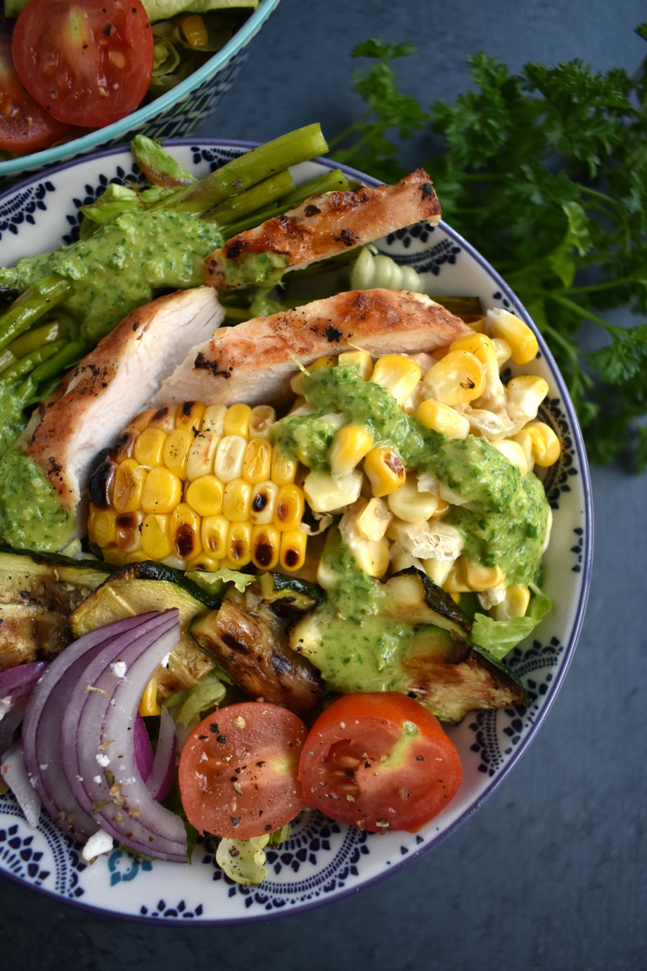 Chicken Chimichurri Salad is loaded with grilled chicken, corn, asparagus, zucchini, red onion and tomatoes and topped with a fresh parsley and cilantro herb chimichurri vinaigrette. www.nutritionistreviews.com