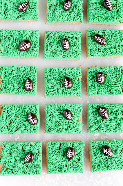 Soft peanut butter cookie bars with a vanilla frosted football field and chocolate covered almond footballs! This cookie cake is easy to make and perfect for game day.