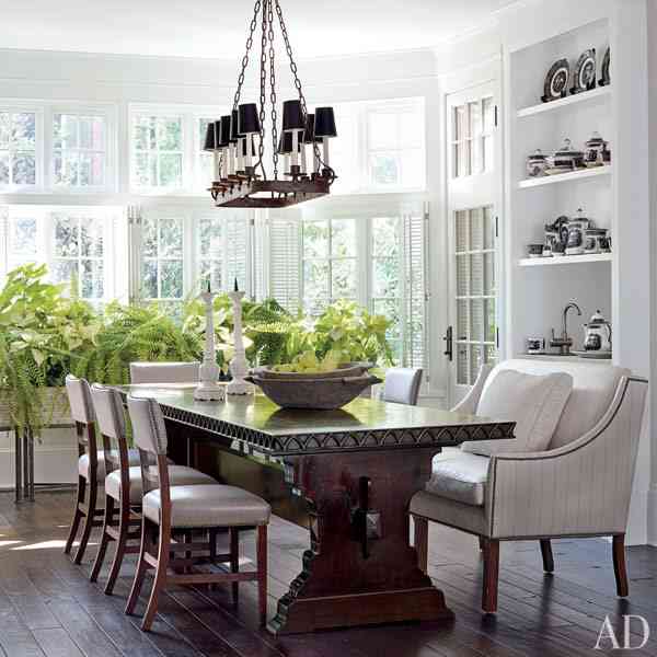 Dining room with restained wood floor and table, matching chandeliers, white cabinets and panned windows