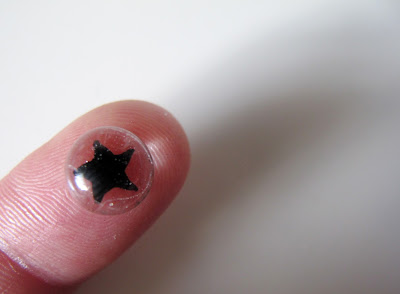 Dolls' house miniature glass star paperweight displayed on a finger.