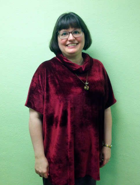 Person standing in front of blank wall showing off velour tunic