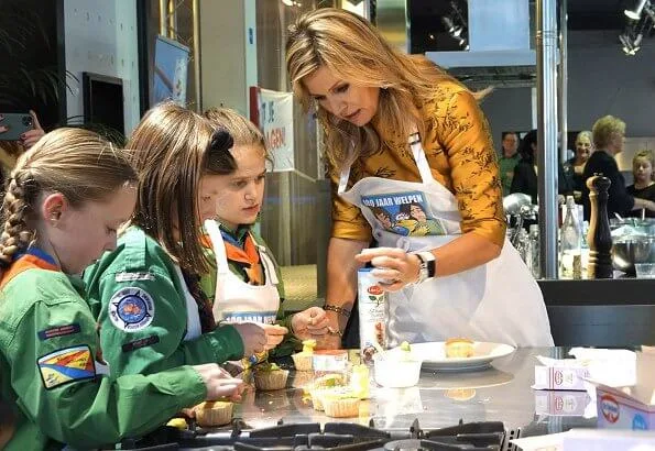 Queen Maxima wore a floral print satin yellow top and floral print blue skirt by Natan. Queen Maxima visited the Scouting Netherlands Cubs