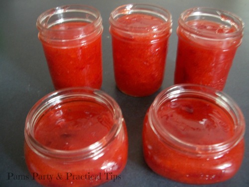 Pouring strawberry jam into jars 