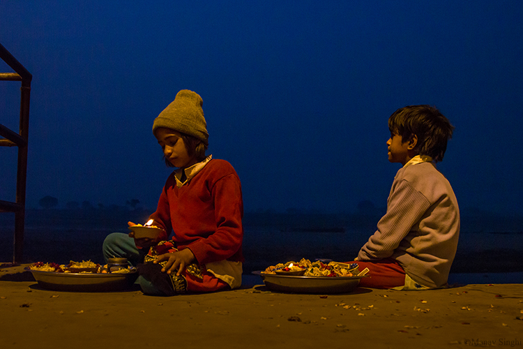 Brother and Sister selling Diyas decorated with flowers and waiting for customers to offer to Yamuna River at Vrindavan as part of prayer.