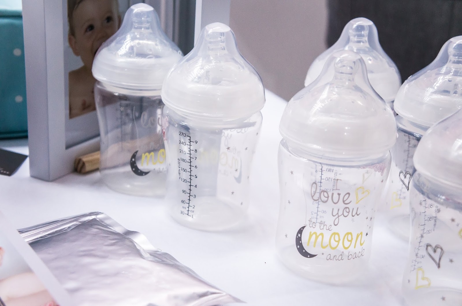 baby bottles with text love you to the moon and back on display at nuby big reveal event