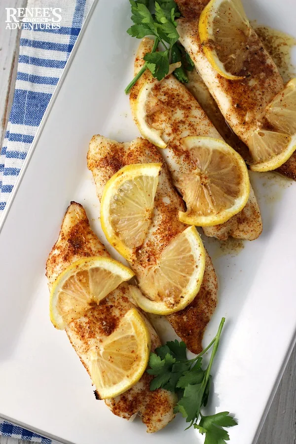 Cajun Baked Tilapia Loins by Renee's Kitchen Adventures on a white platter with lemons