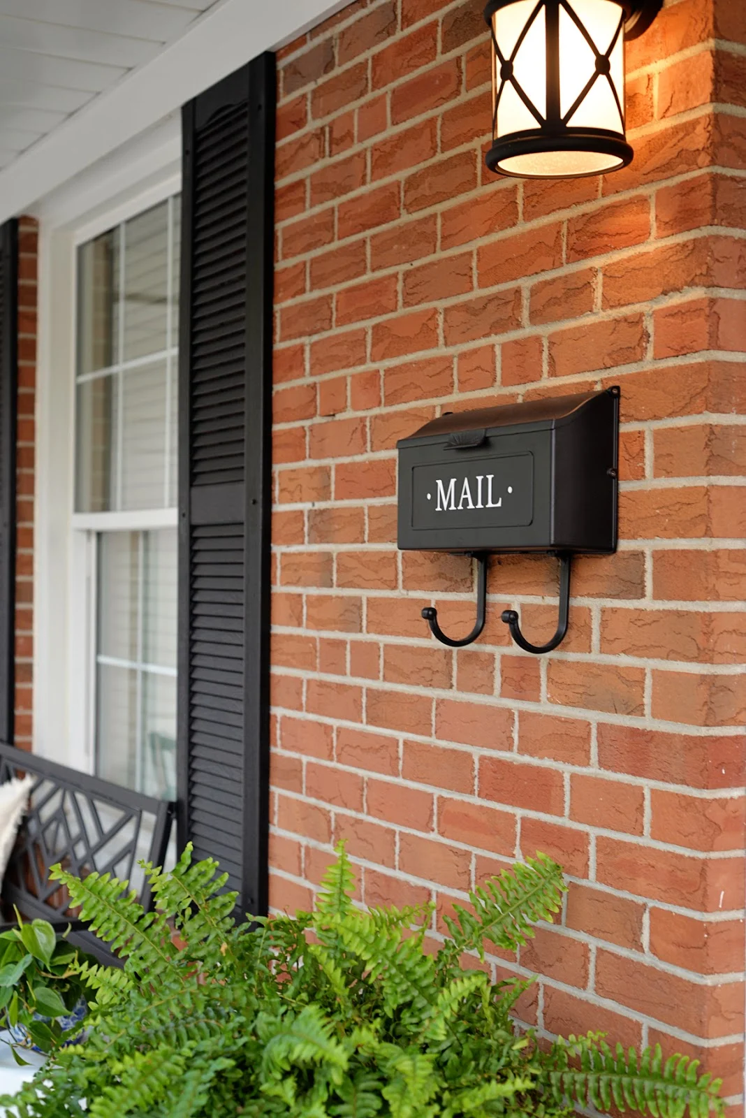 front porch decorating ideas for summer, red brick house with black shutters and mailbox decal