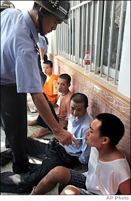 A Chinese police officer lights a prisoner's last cigarette, moments before his execution.