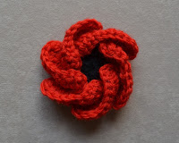 "Hope Bloom" by Jenny King before blocking. The six petals are curled inwards over themselves.
