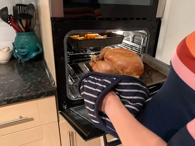 Pulling out a roasting chicken from an oven