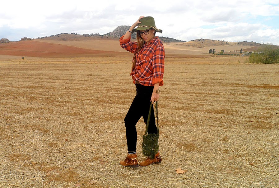Camisa de cuadros con vaqueros rotos, botas boho, sombrero y bolso