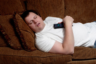 Guy Laying on the sofa or couch sleeping with a remote in his hand
