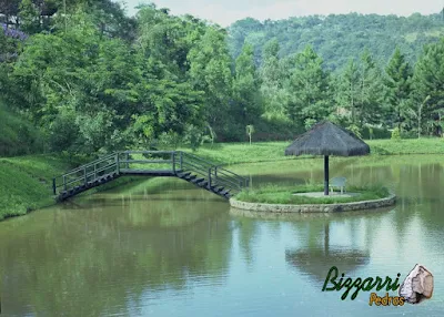 Construção do lago com a ilha no meio com os muros de pedra, o quiosque de piaçava e a ponte de madeira. Construção de lagos em Mairiporã-SP.