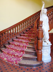 Large statue at the foot of a curved staircase.