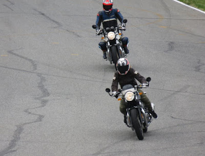 Two motorcycles take a curve on race track.