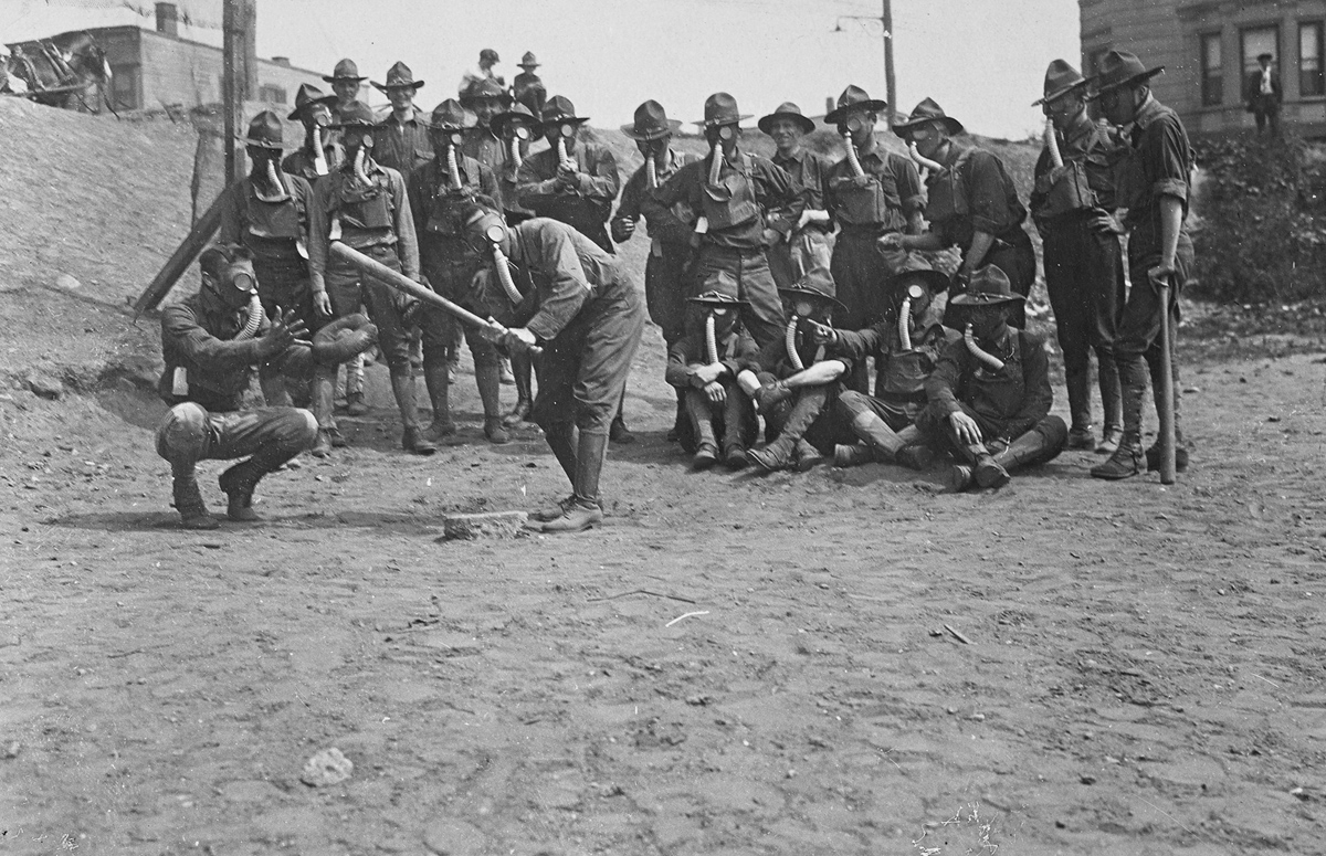 Soldiers playing baseball while wearing gas masks. Original caption: It is not troubling these soldiers any to play ball while wearing their gas masks. Gas Defense Plant, Long Island, New York.