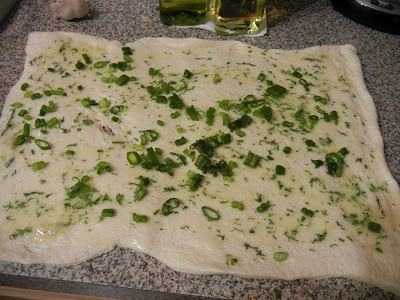 dough rolled out into a rectangle with Chive Garlic and Herb on it on a counter top 