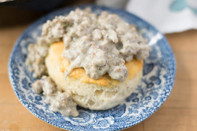 A biscuit on a plate smothered in the sausage gravy. 