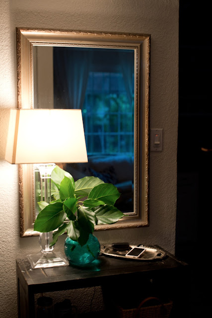 Entryway vignette using a lamp, vase, and mirror.