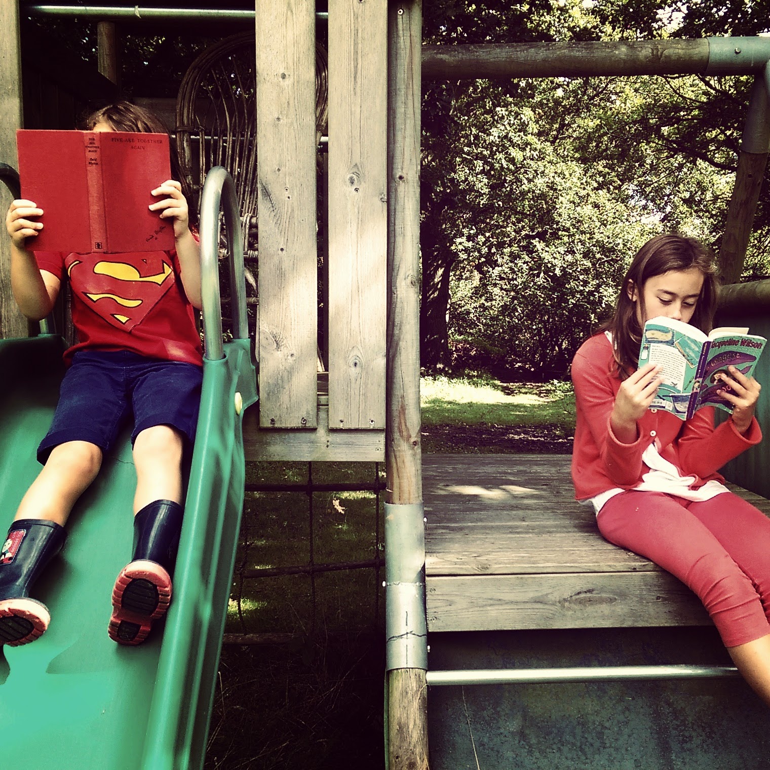 Two girls reading books on play equipment