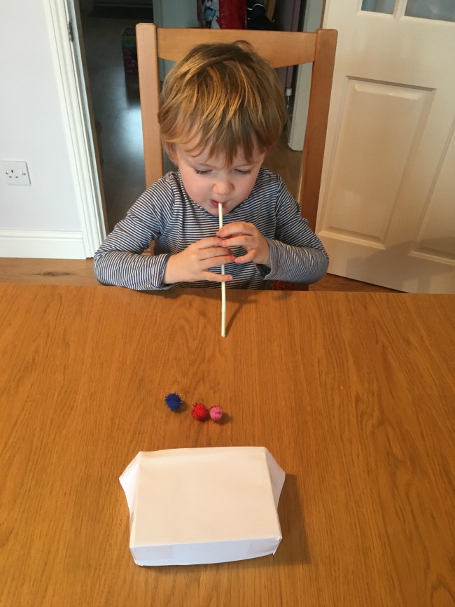 5-minute-games-for-toddlers-blow-football-image-of-toddler-with-straw-and-pompom-on-table