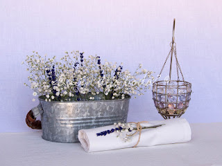 Cubo de cinc con lavanda y paniculata, acompañado de detalle de servilleta y lámpara de cristales