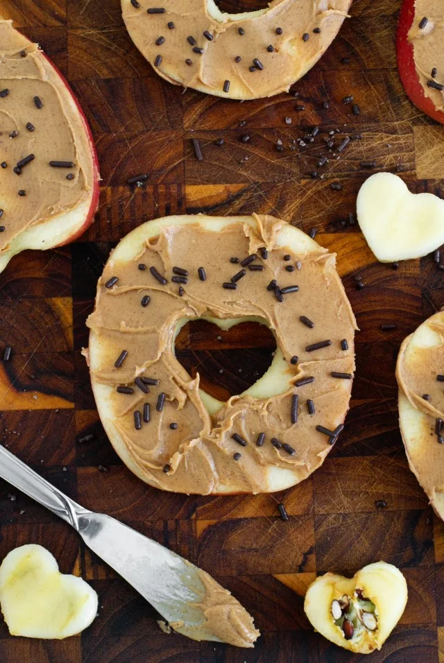 Sliced Apple "Donuts" are a fun and healthy play on yeast doughnuts, but instead of dough, they're made with sliced apples, peanut butter for frosting, and a sprinkle of chocolate jimmies.