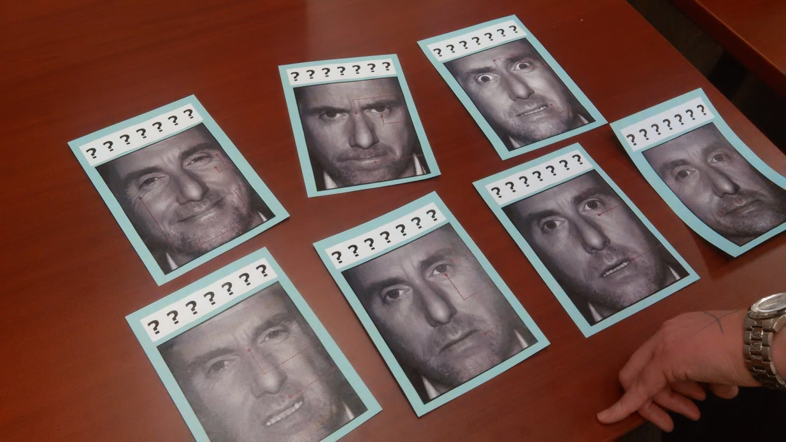 Photo of a table covered in photos of a man making various expressions.