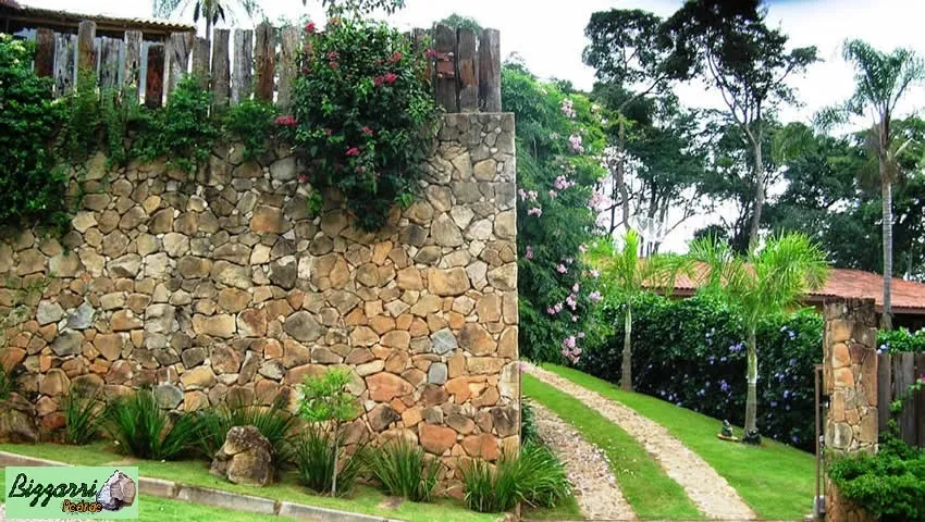 Detalhe do muro de pedra moledo com os caminhos de pedra e a execução do paisagismo.