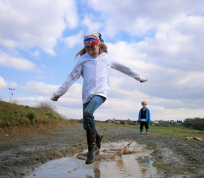 girl jumping in muddy puddle wearing next olympic supporters scarf style for london 2012
