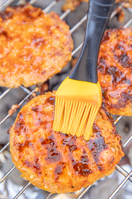 Buffalo Chicken Burgers Recipe - SO good! I like these better than regular beef burgers! SO much amazing flavor! Ground chicken, bread crumbs, cheddar cheese, ranch seasoning, and buffalo seasoning. Can form into patties and freeze for later. Can cook on the grill or on the stove. Brush with hot sauce to kick up the heat. Top with ranch or blue cheese dressing. Also great topped with slaw! #bbq #grilling #chicken #groundchicken #burger #chickenburger ground chicken burgers cooking on the grill
