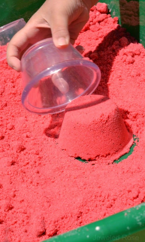 Watermelon Moon Sand Recipe- If you are unfamiliar with moon sand it is truly amazing stuff.  It is mold-able but crumbly and produces the best sandcastles.  It is really easy to make at home, too.