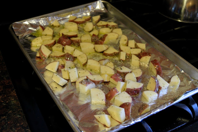 Potatoes laying on a foil lined baking sheet.  