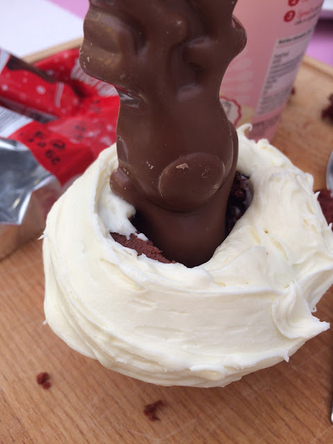 Red velvet cup cake with vanilla frosting and a chocolate reindeer in its centre