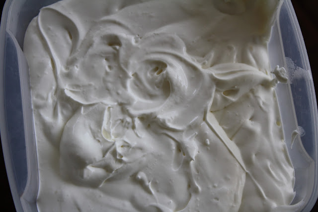 Overhead shot of cream cheese frosting in plastic container. 