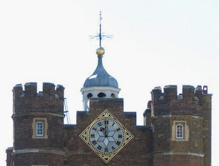 Twin brick towers with a clock in the centre on a diamond-shaped background