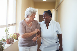 An elderly woman and a physical therapist walking down the hall smiling in Midlothian, TX