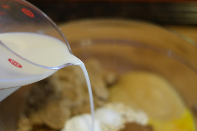 The almond milk being added to the ingredients in the mixing bowl.