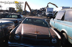 Scrap yard monsters waiting to devour this 1974 Chevy Monte Carlo. 