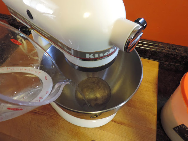 Water and yeast being added to a Kitchenaid mixer. 